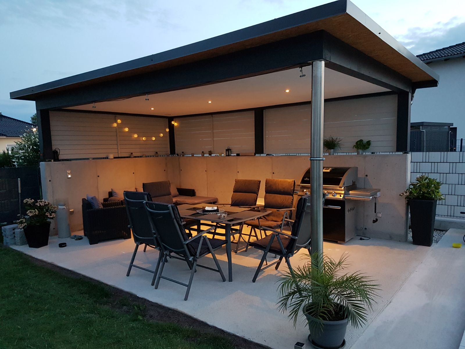 Überdachte Gartenterrasse mit Flachdach, Sitzbereich und Außenküche